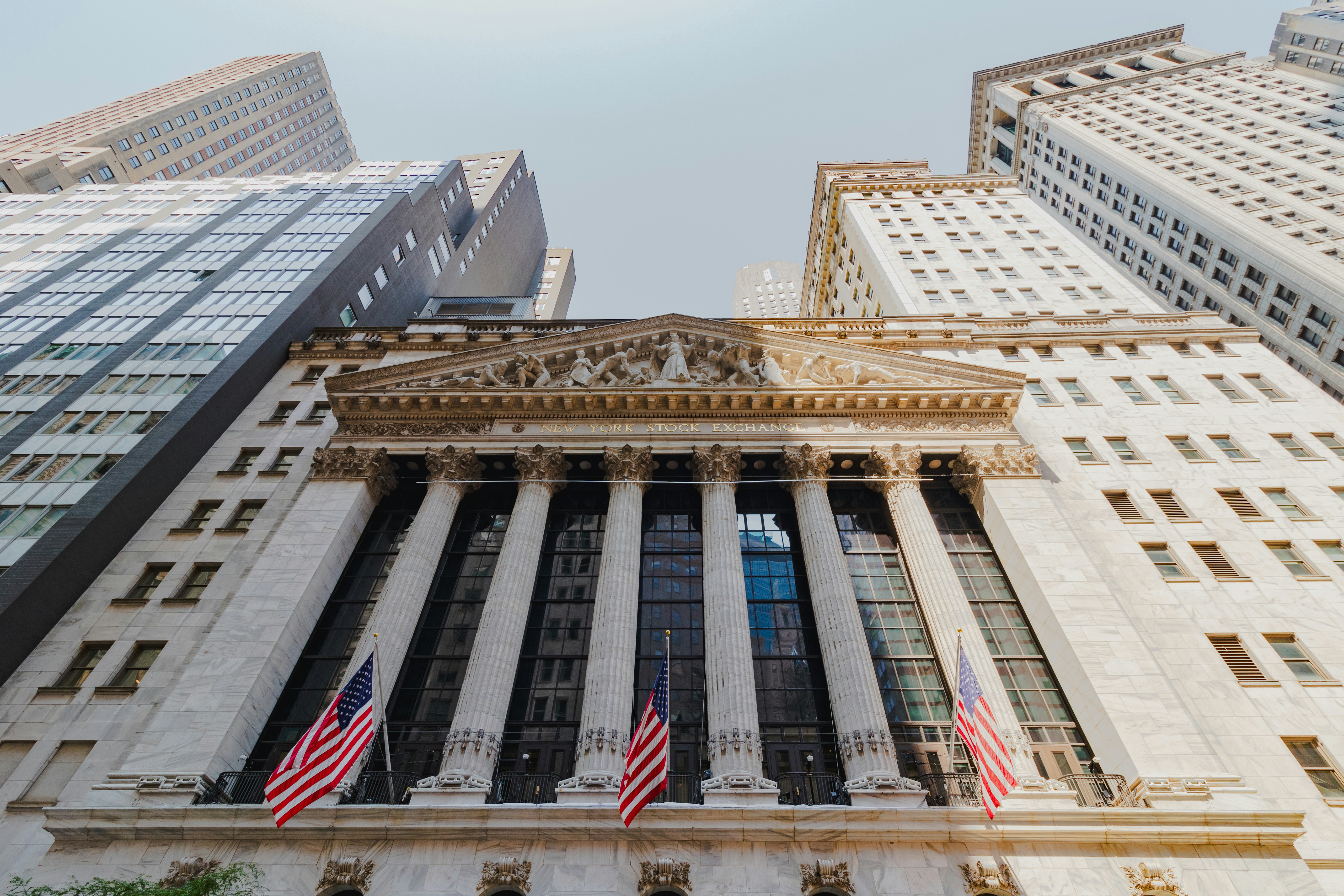 Facade of the New York Stock Exchange with columns and American flags.