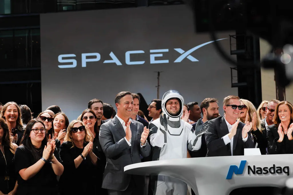 SpaceX team during Nasdaq’s opening bell ceremony following the company’s IPO debut, with the SpaceX logo visible in the background.