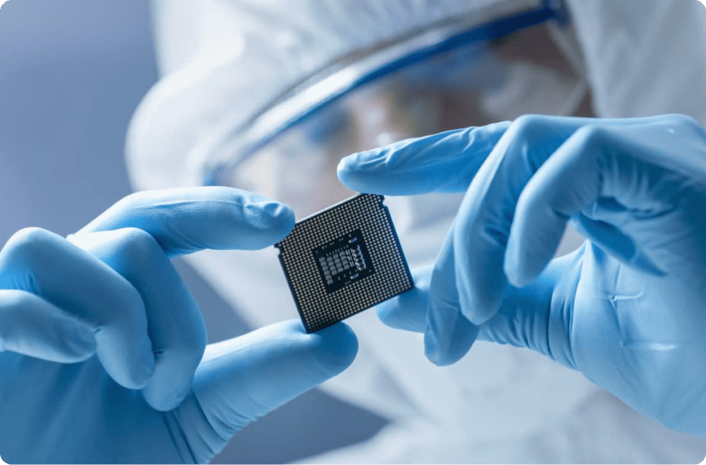 An engineer in a cleanroom holds a semiconductor chip