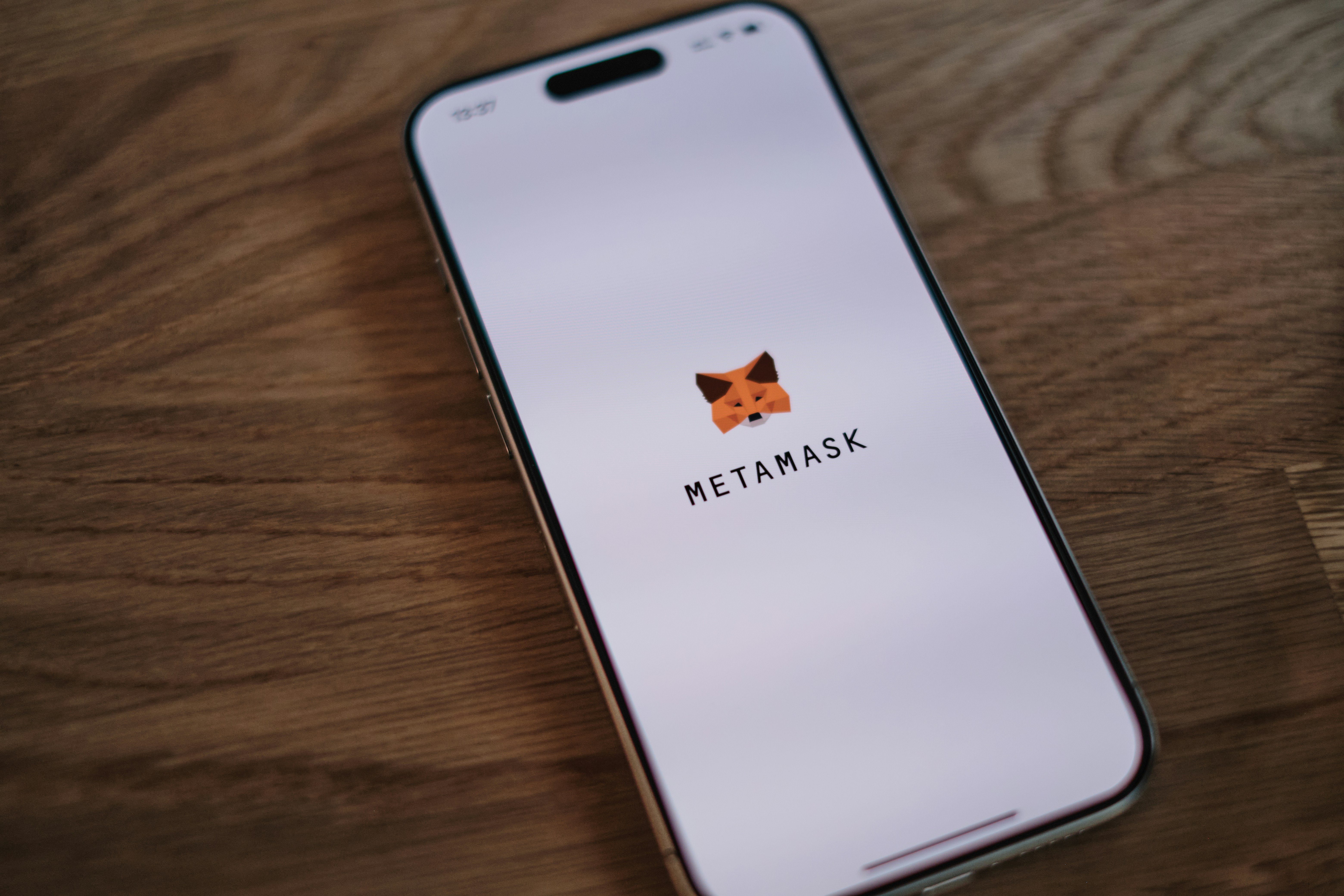 A smartphone displaying the MetaMask app lies on a wooden table