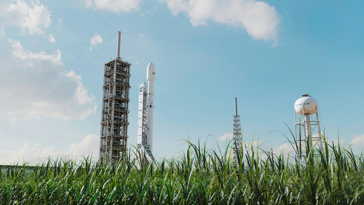 Ракета Falcon 9 компании SpaceX на стартовой площадке рядом с башней обслуживания и водонапорной башней.