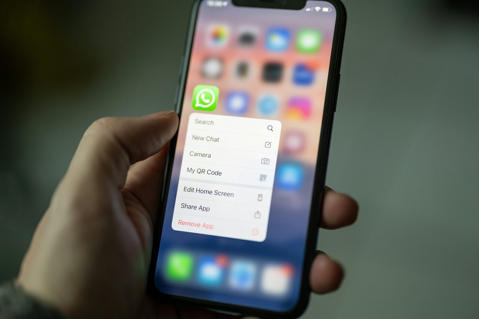 Смартфон с открытым меню WhatsApp в руке пользователя.