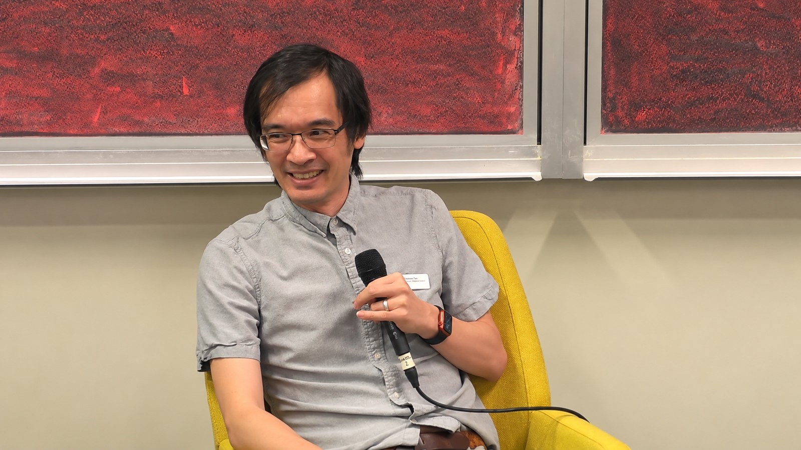 Mathematician Terence Tao holding a microphone at an IPAM discussion on mathematics and artificial intelligence.