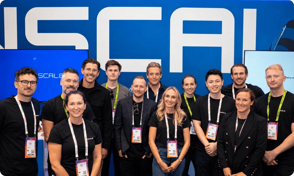 Команда Nscale на выставочном стенде с крупным логотипом компании.