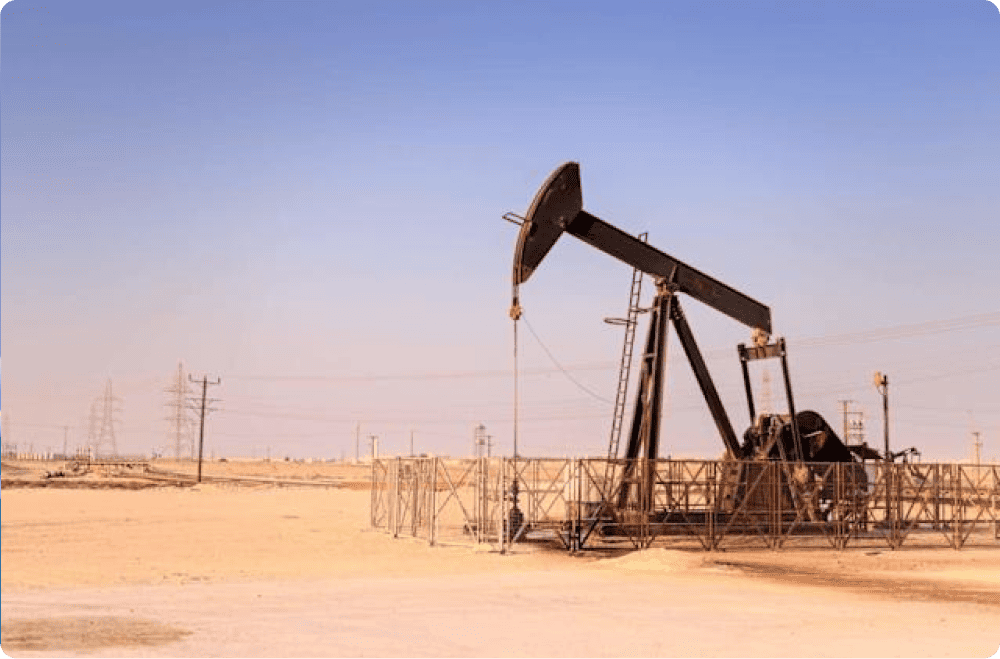 Oil pump jack in a desert landscape with power lines in the background