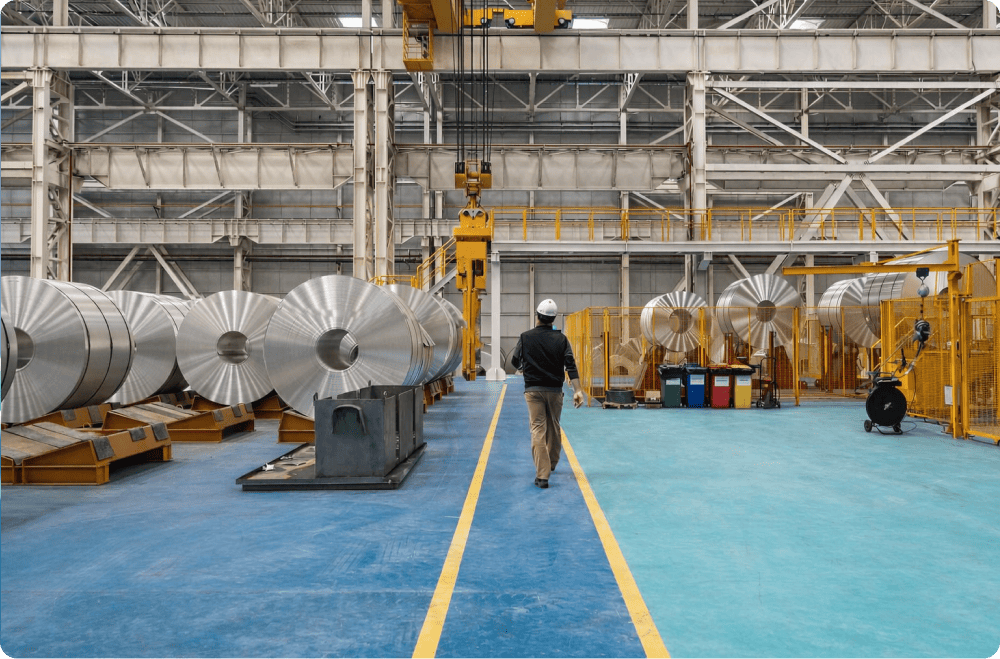 Industrial workshop with metal coils and a worker walking along the production line